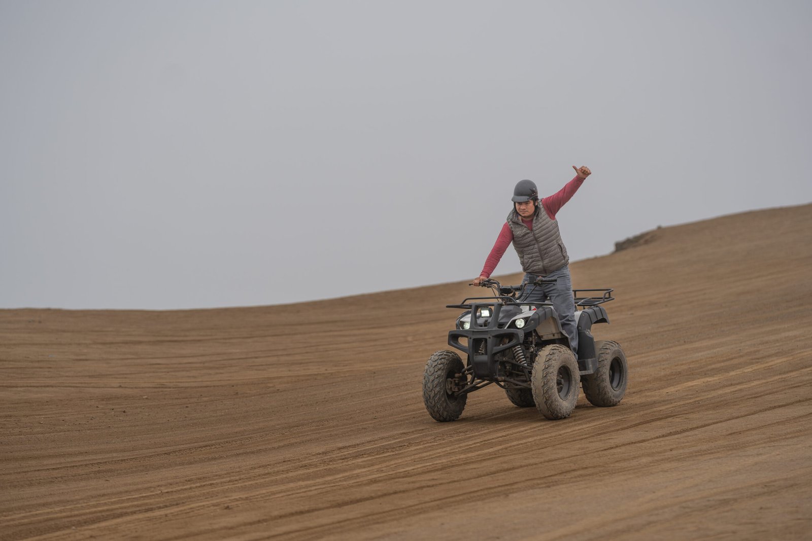 Man gesturing with the finger up to be okay while driving a quad bike out of a road