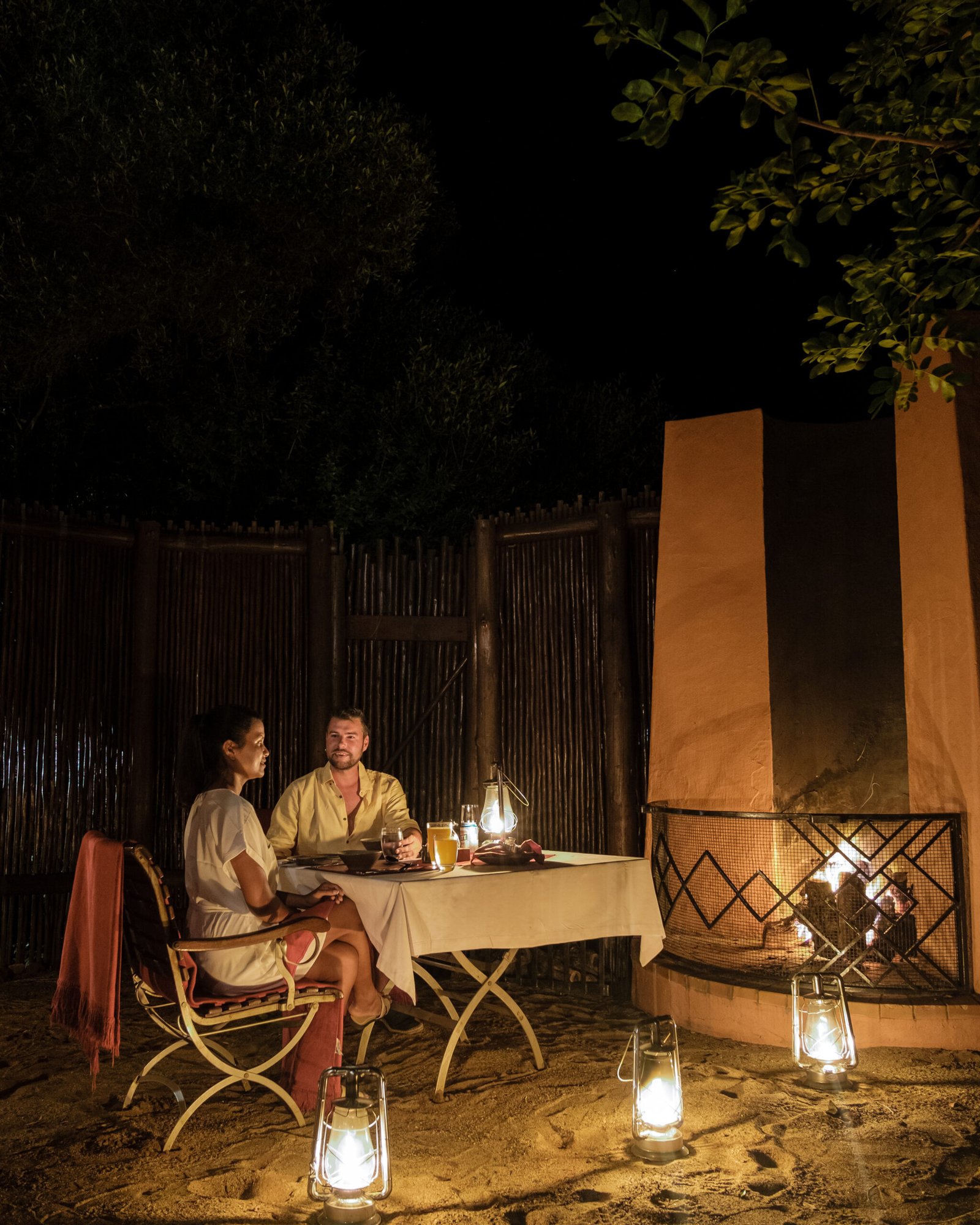 South Africa Kwazulu natal, a luxury safari lodge in the bush of a Game reserve Savanah, couple men and Asian woman having dinner by candle light