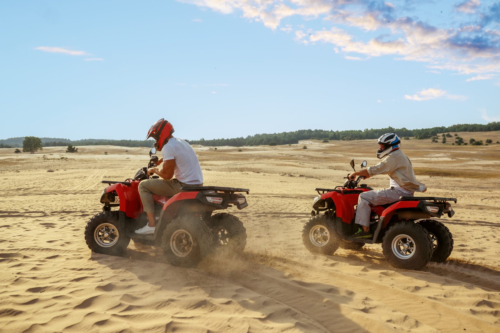 Two men in helmets ride on atv in desert. Male persons on quad bikes, sandy race, dune safari in hot sunny day, 4x4 extreme adventure, quad-biking