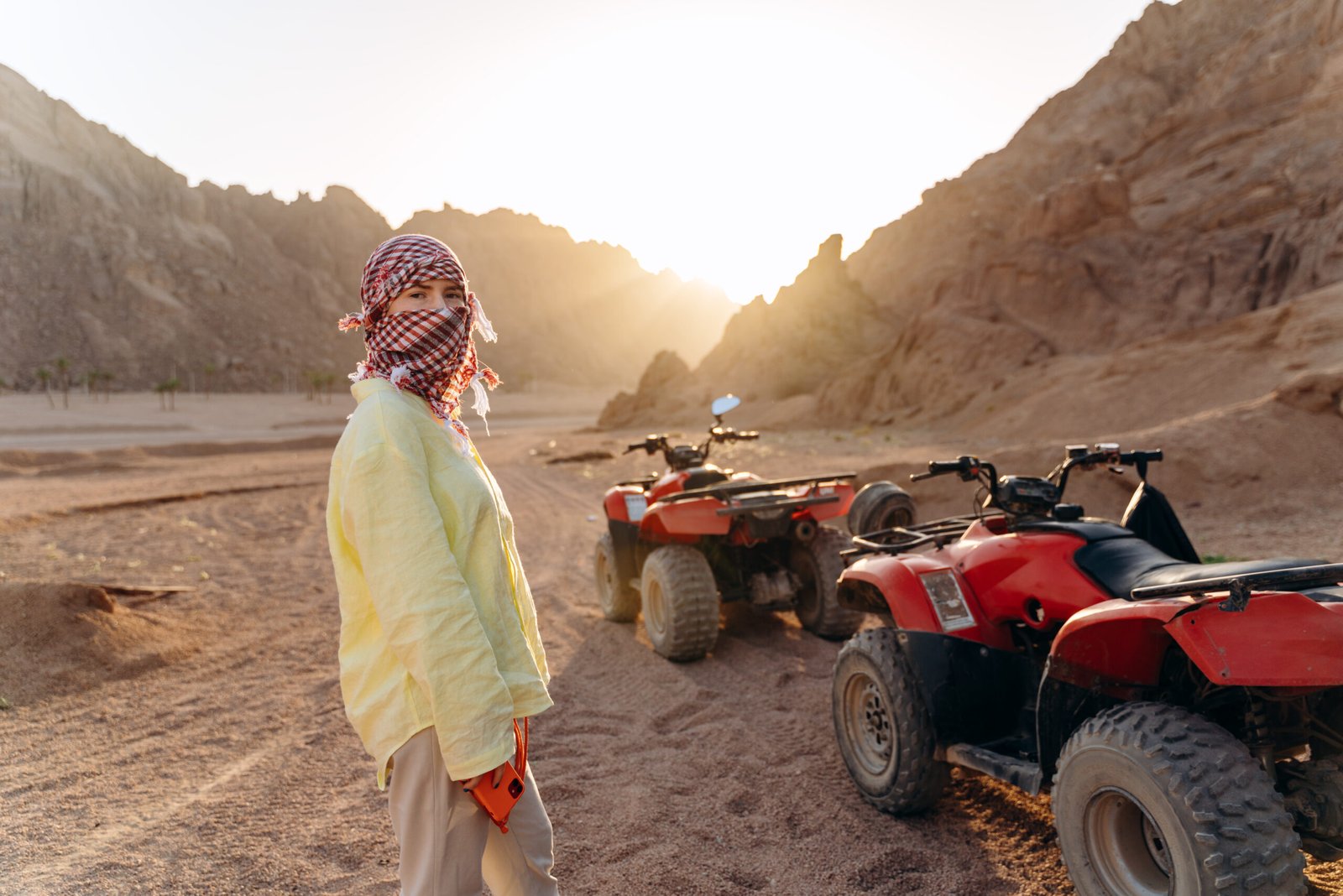 Young girl with a covered face preparing for a desert safari on ATVs. A fun journey through the desert